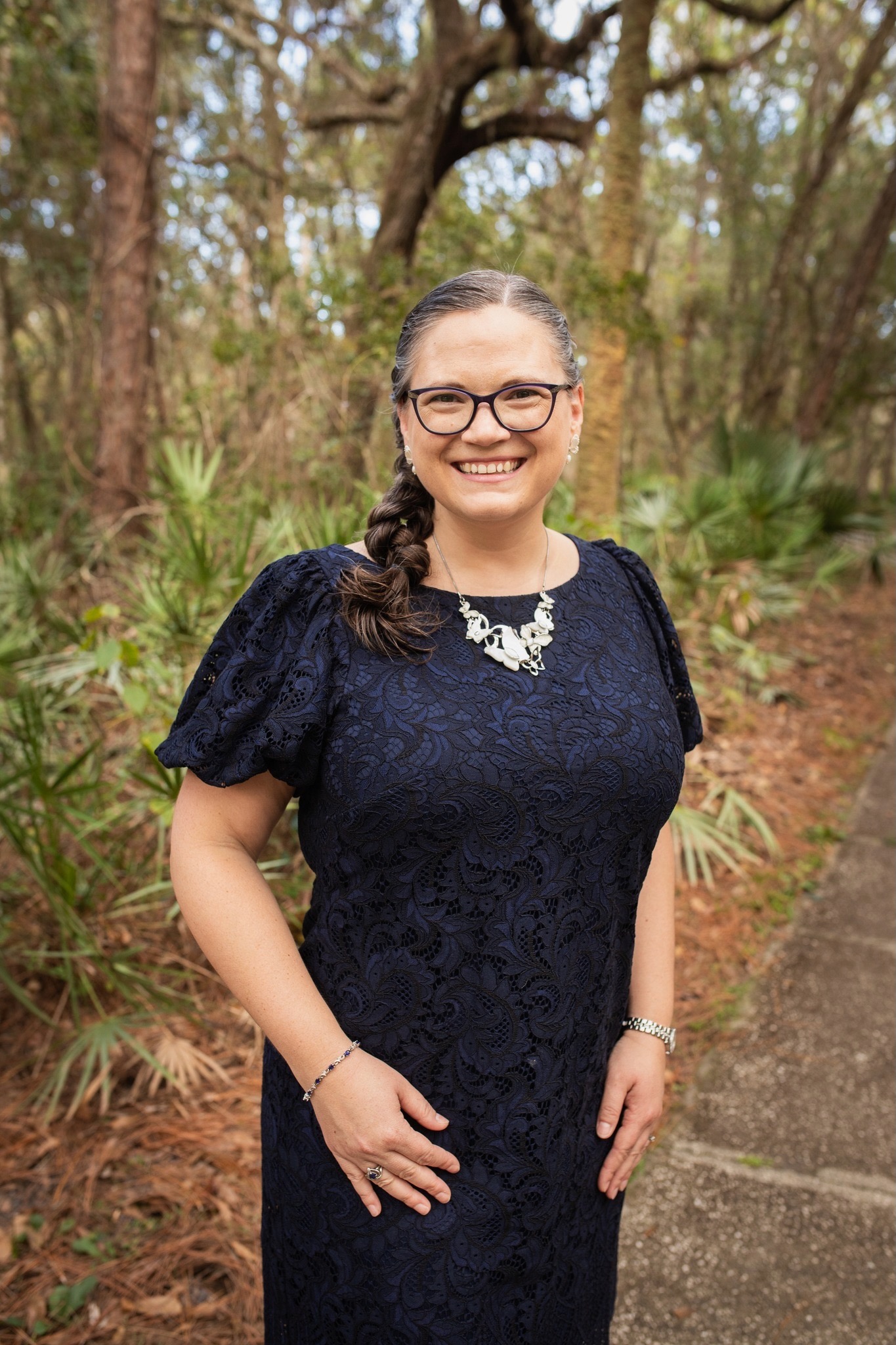 Melody Dawn smiling outdoors in a navy dress.